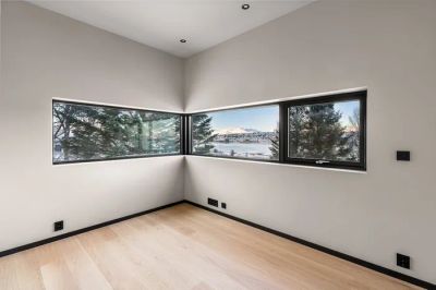 Minimalistyczny salon z dużym oknem i pustą przestrzenią, idealny na domową strefę do ćwiczeń